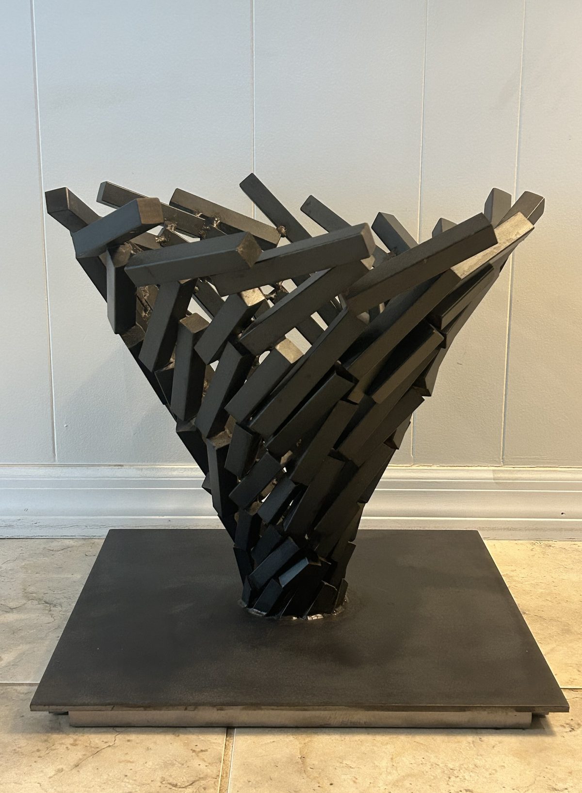 Blackened steel sculpture, twisting funnel of welded steel bars