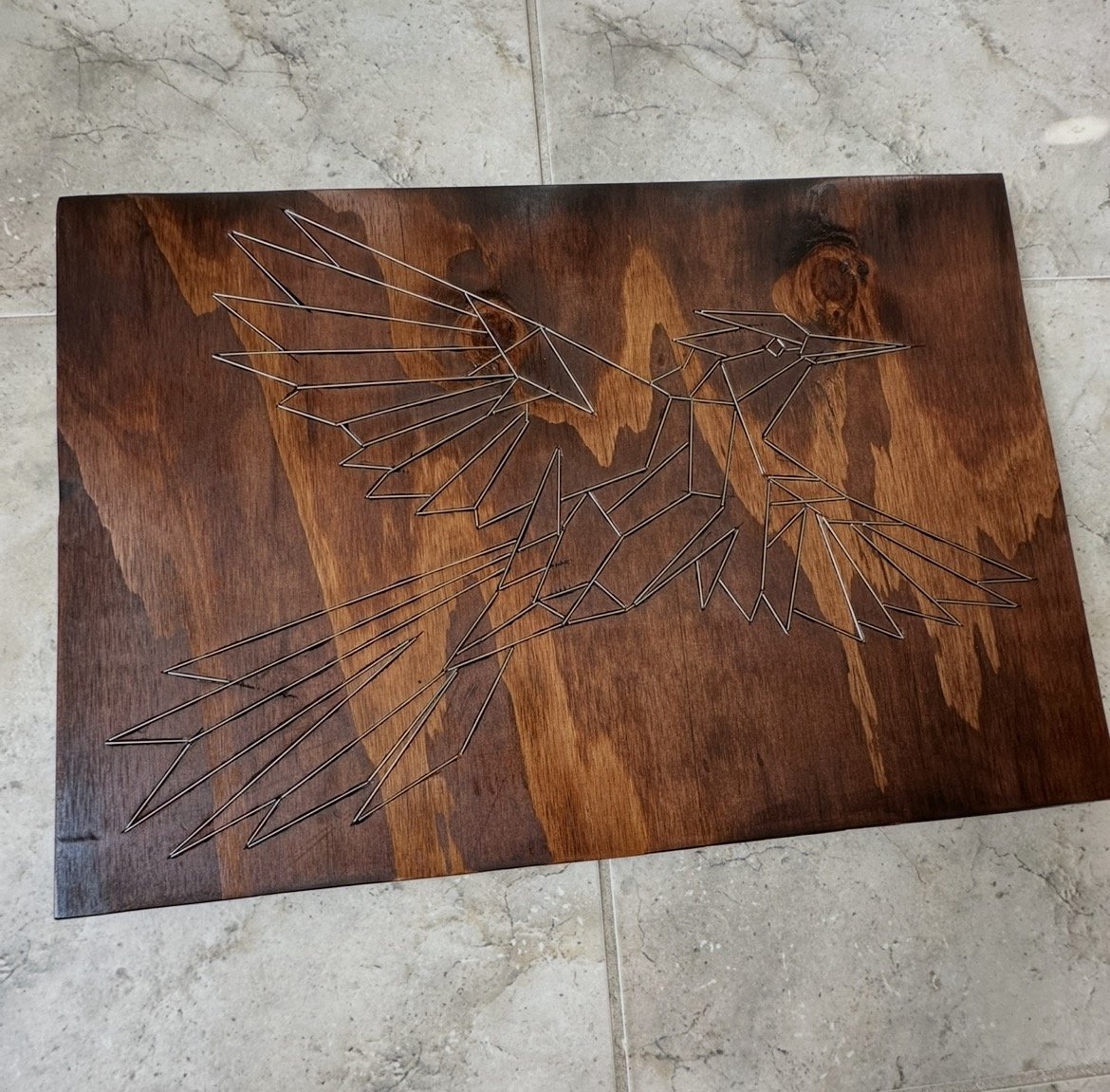 Sparrow, a stained wood panel engraved with a bird in flight and inlaid with stainless steel rod